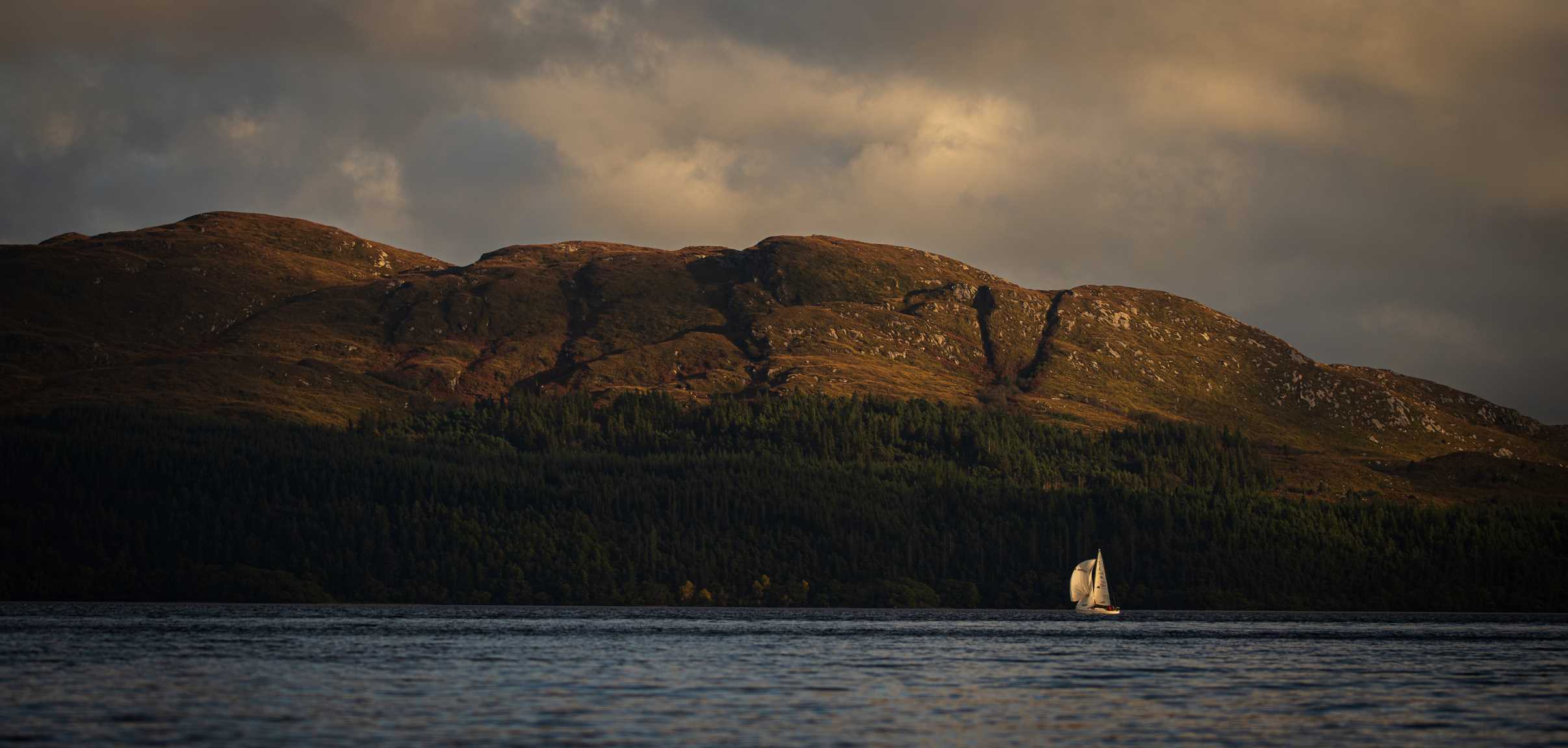 View of the coast in the evening with a yacht in the distance